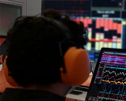 Driver using a racing simulator with steering wheel and telemetry displays, overlaid with digital twin icon.