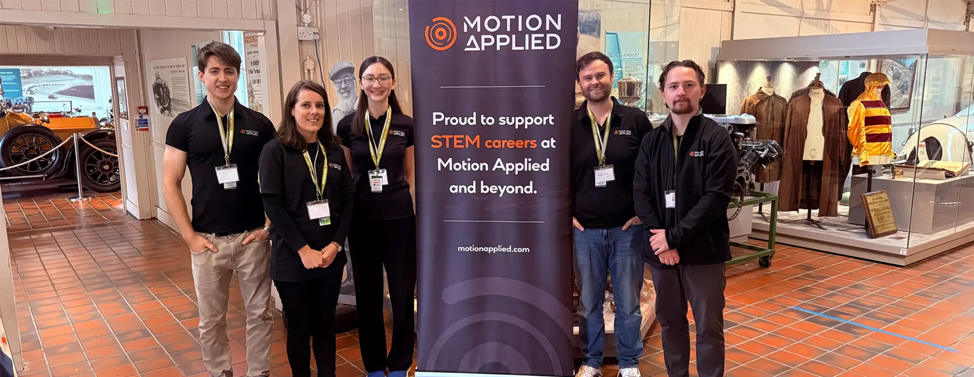 Five people stood in front of a Motion Applied banner at Brooklands STEM event